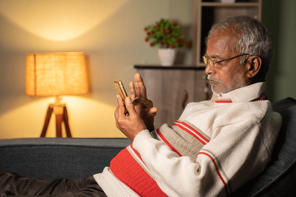 A picture of an older man using a smartphone to take part in research at home
